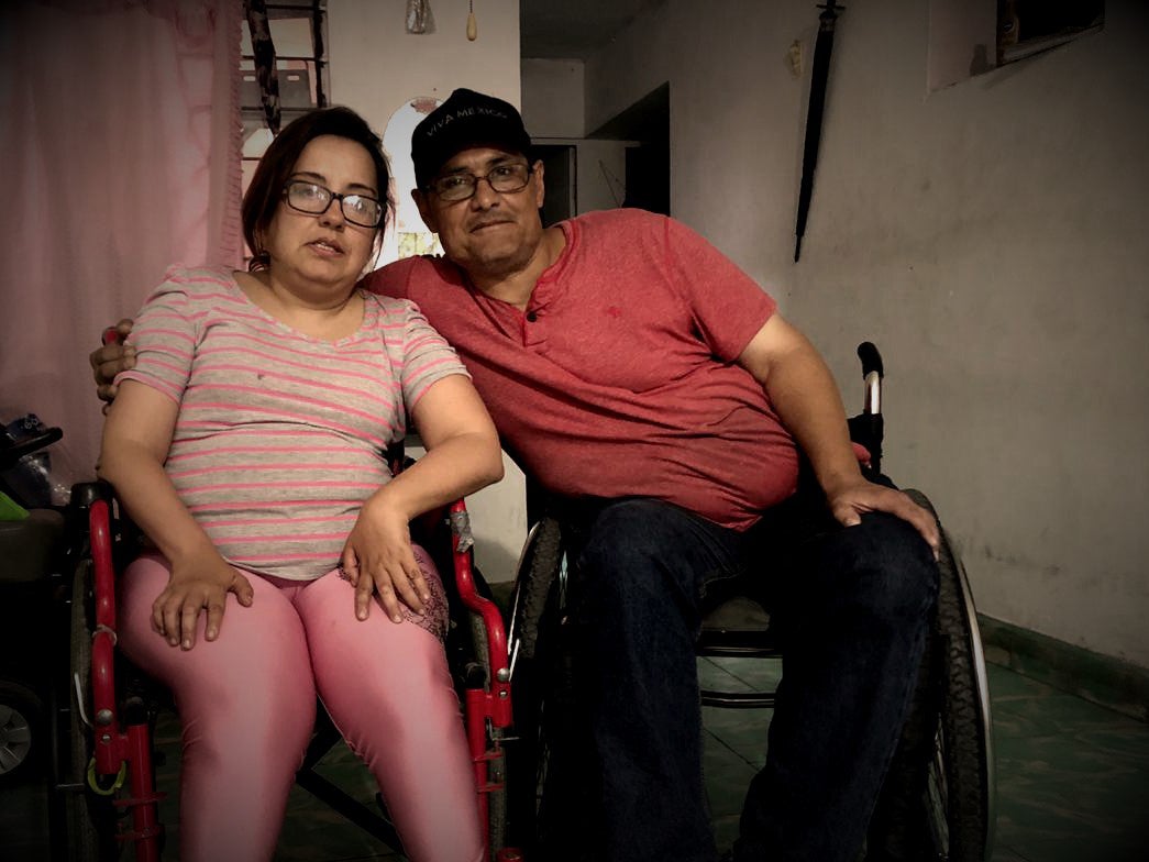 A man and woman in wheelchairs pose for a photo 