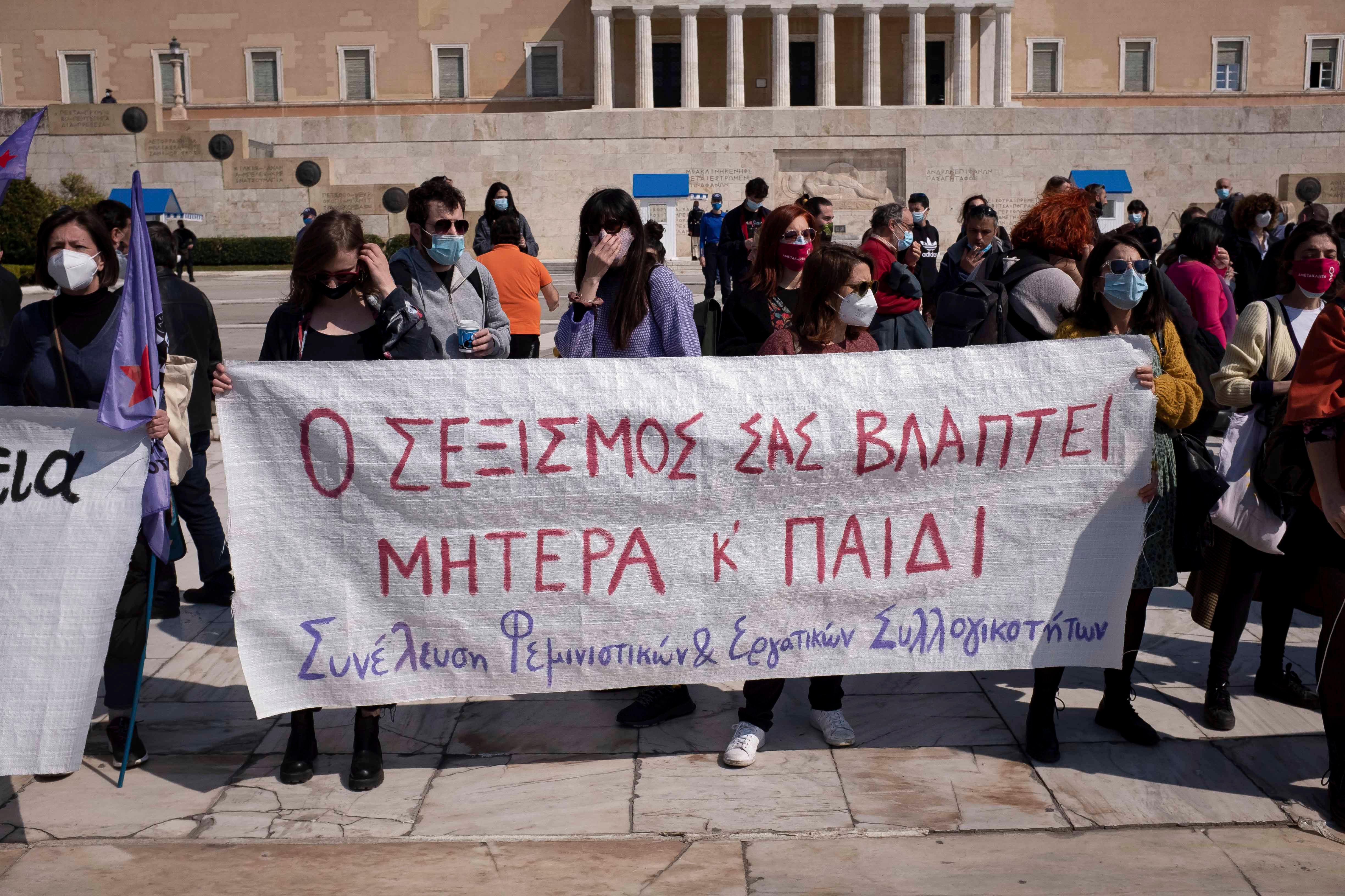 Protesters in Athens, Greece on March 27, 2021 stand outside the Greek Parliament displaying a banner that reads “your sexism is harming both mother and child” against a new law that introduces presumptive co-custody of children, even in cases of domestic violence.