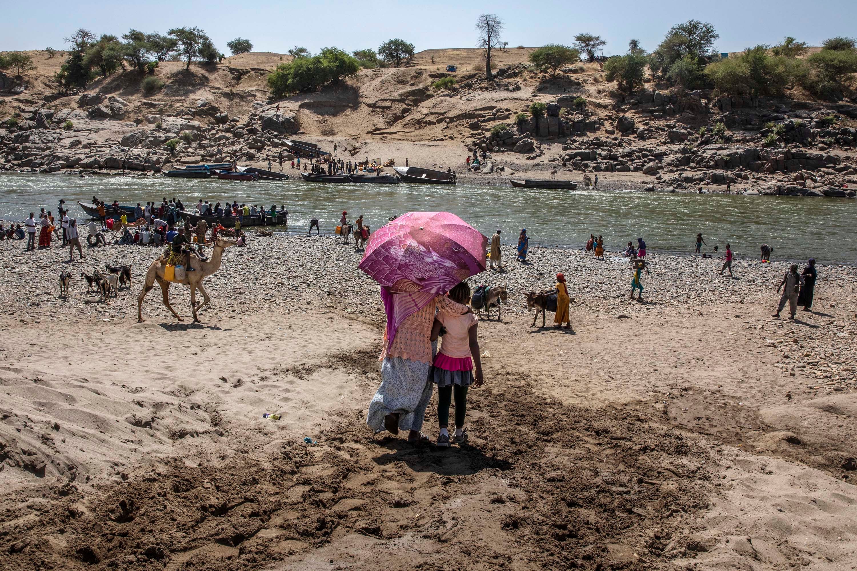 Des réfugiés ayant fui le conflit dans la région du Tigré en Éthiopie, en traversant la rivière Tekeze marquant la frontière entre l'Éthiopie et le Soudan, photographiés peu après leur arrivée sur le territoire soudanais, près de Hamdayet (est du Soudan), le 21 novembre 2020. 