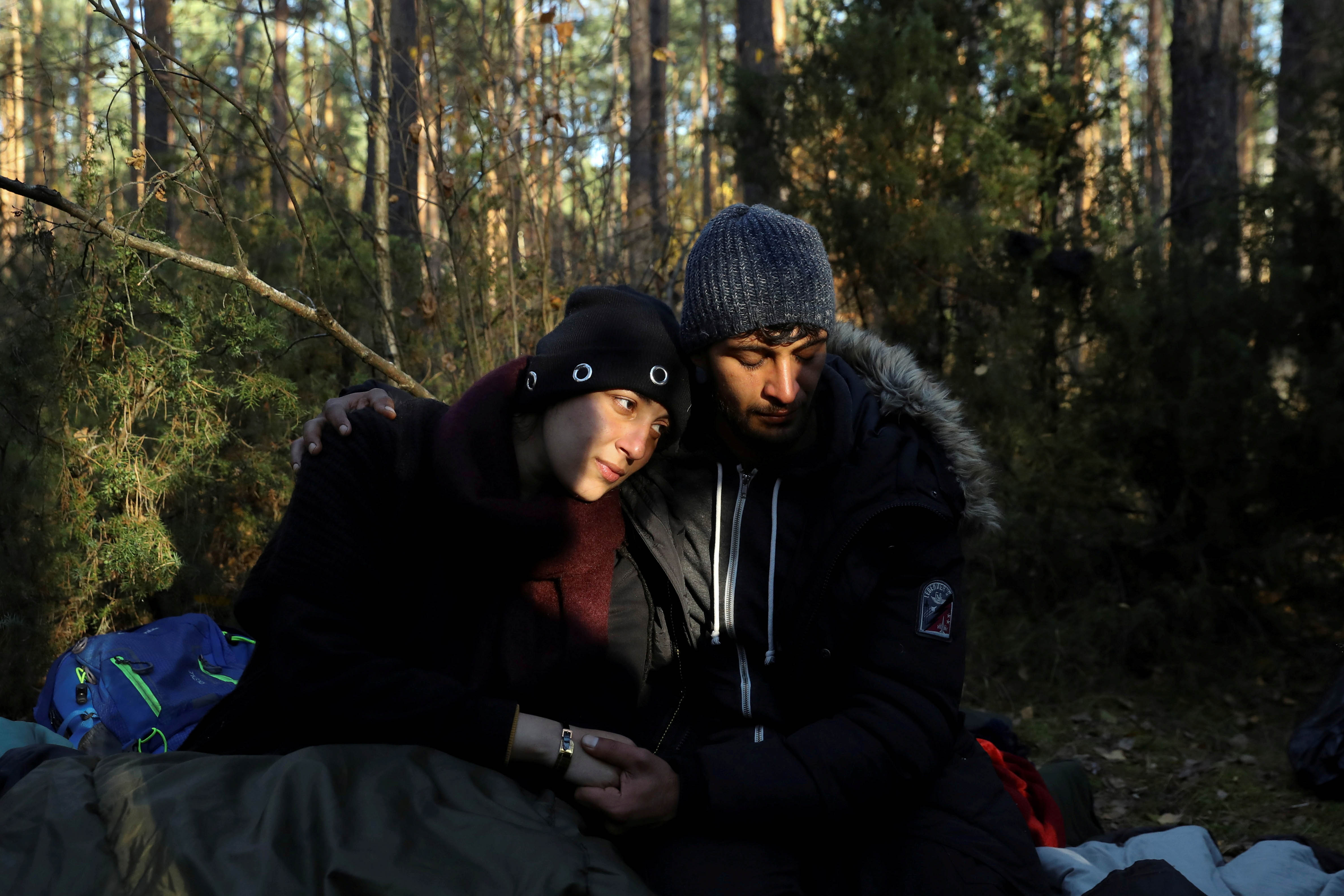 Syryjczycy Sara (26 l.), i Hassan (24 l.), siedzą na ziemi w polskim lesie w Lewoszach, po przekroczeniu granicy z Białorusią, 29 października 2021 r.