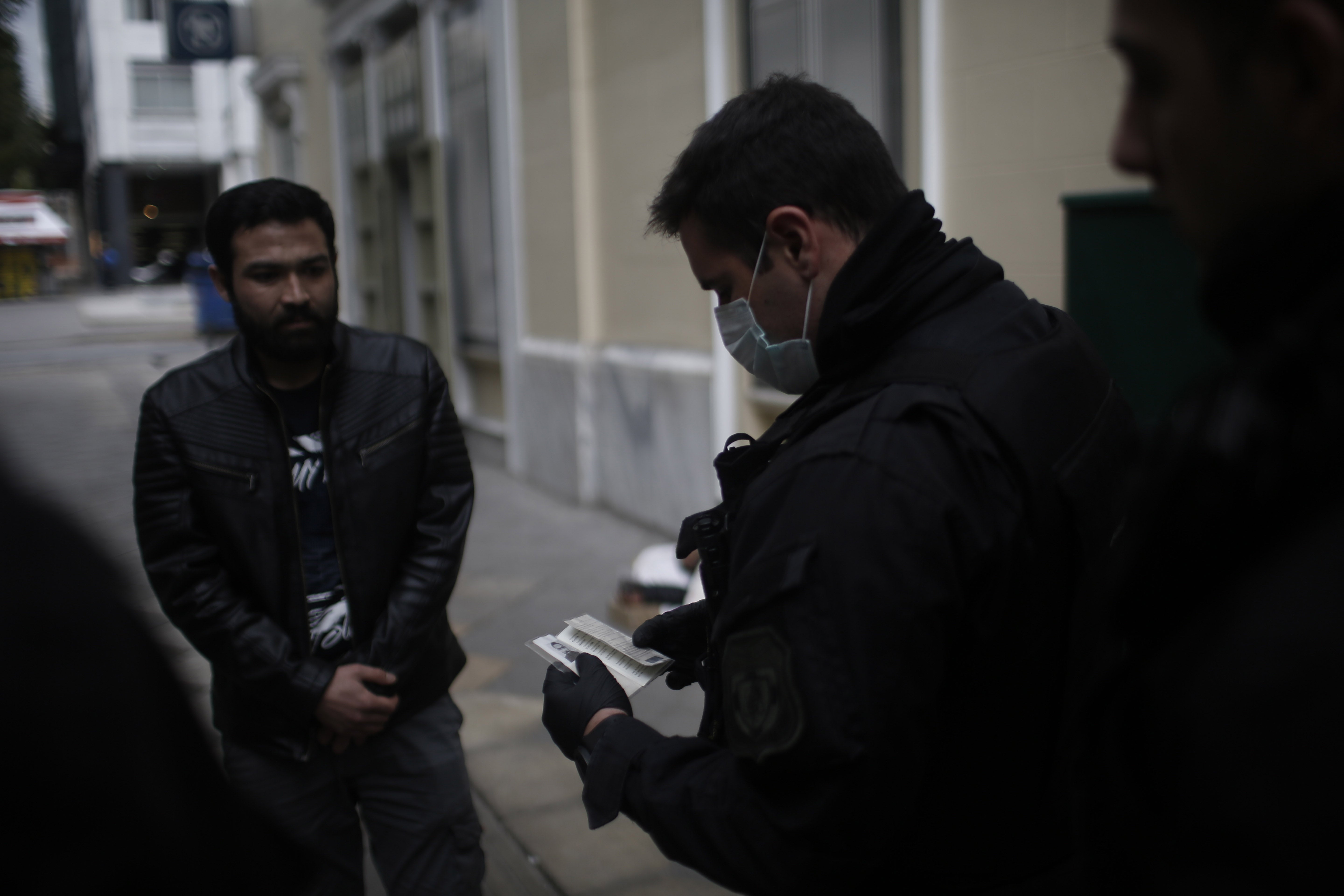 Αστυνομικοί ελέγχουν τα έγγραφα και τις άδειες ανθρώπων στους δρόμους της Αθήνας, Ελλάδα, 23 Μαρτίου 2020.