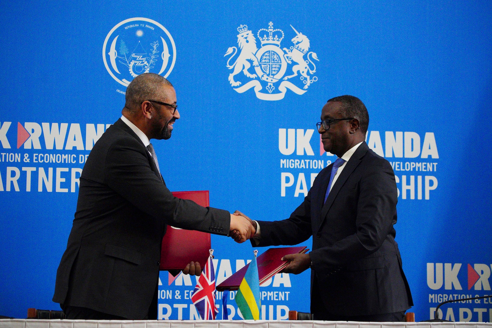 Britain's Home Secretary James Cleverly, left, and Rwandan Minister of Foreign Affairs Vincent Biruta shake hands after signing a new treaty in Kigali, Rwanda, December 5, 2023.