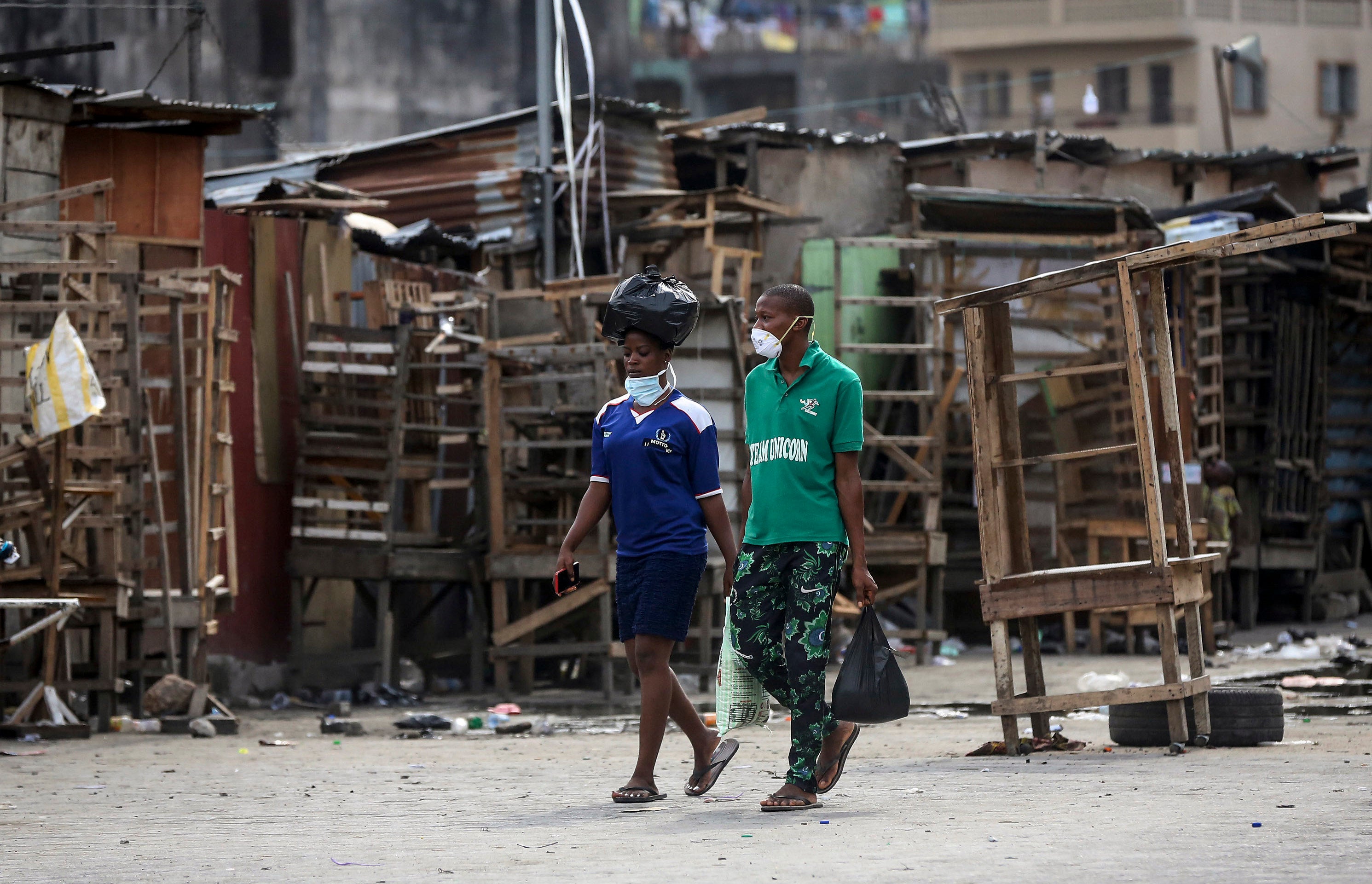People walk past closed street stalls and shops in Lagos, Nigeria on March 26, 2020 during a government-imposed lockdown to halt the spread of COVID-19. 2020 AP Photo/Sunday Alamba.