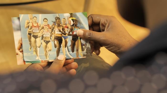 A woman holds a photo of a group of female runners competing