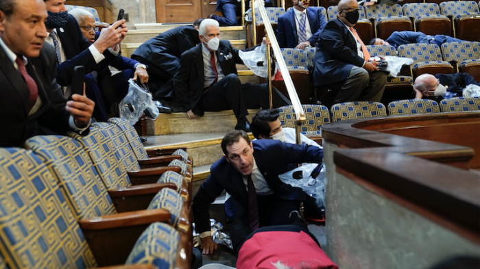 People shelter in the House gallery as protesters try to break into the House Chamber at the U.S. Capitol on Wednesday, Jan. 6, 2021, in Washington.