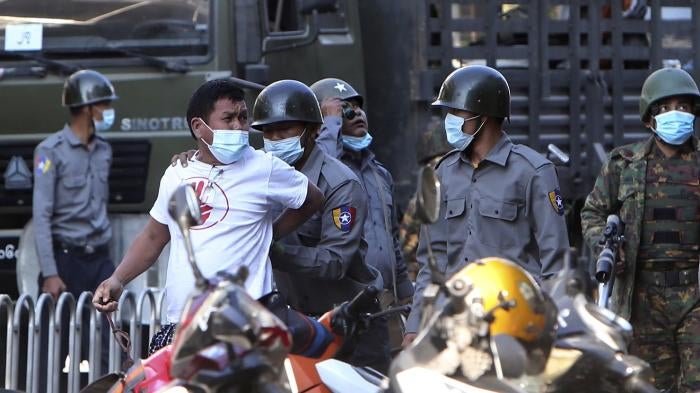 A man is held by police during a crackdown on anti-coup protesters holding a rally in front of the Myanmar Economic Bank in Mandalay, Myanmar on February 15, 2021.