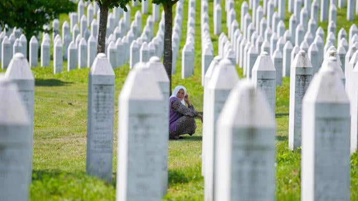 A woman among the graves of victims of the Srebrenica genocide, at the memorial cemetery in Potocari, near Srebrenica, Tuesday, June 8, 2021.