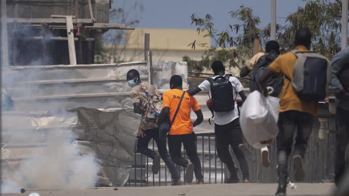 People flee teargas thrown by riot police during a protest against the proposed counterterrorism law and penal code reform at the Cheikh Anta Diop University campus in Dakar, Senegal, June 25, 2021. 