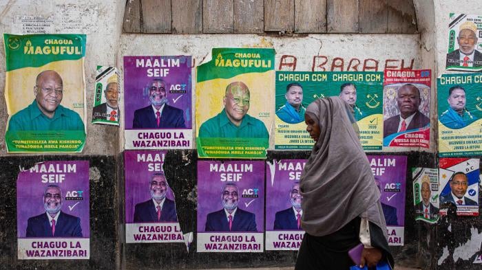 A woman walks past a wall with posters of presidential candidates in Zanzibar’s town on October 24, 2020