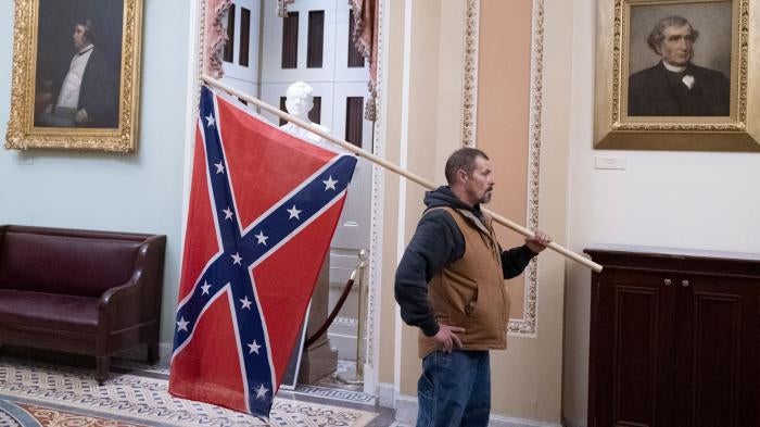 A protester stands with a Confederate flag after storming the Capitol during a Joint Session of Congress in which members were to certify the 2020 Presidential election on January 6, 2021.