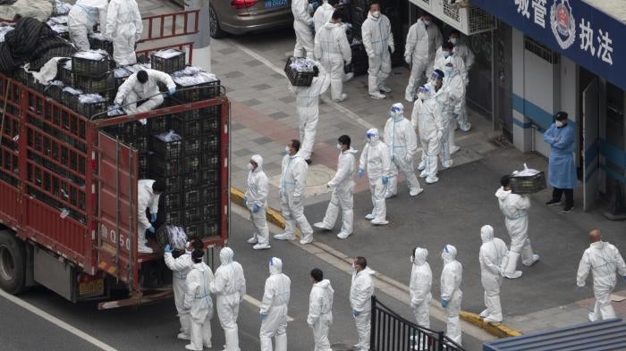 People in PPE load groceries off a truck before distributing them to locals under the Covid-19 lockdown in Shanghai, China, April 5, 2022.