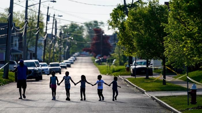 Children walk hand in hand down a street