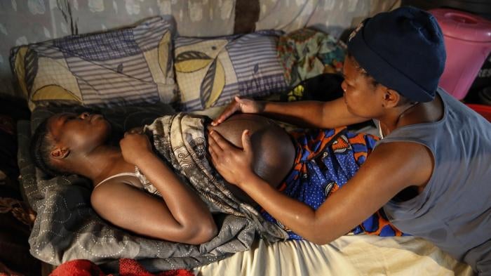 A traditional birth attendant massages a pregnant woman before assisting in delivering her baby in Kibera, Nairobi, Kenya, July 3, 2020.