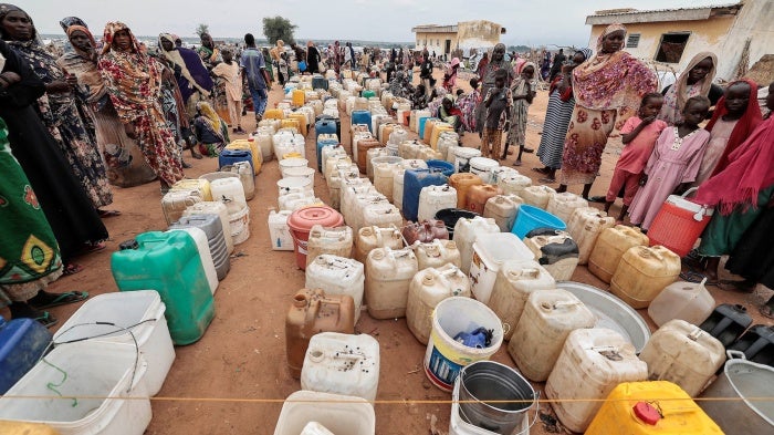 Sudanese women and children who fled the conflict in Geneina, in Sudan's Darfur region, line up at the water point in Adre, Chad, July 30, 2023. 