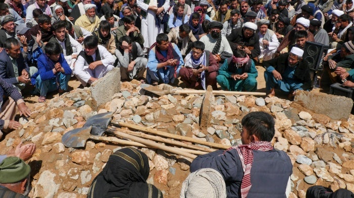 A crowd surrounds a burial site