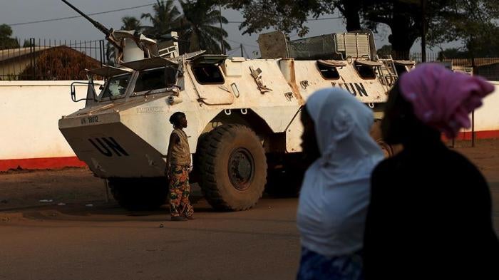 Women walk by a United Nations peacekeeping armored vehicle guarding the outer perimeter of a school used as an electoral center at the end of the presidential and legislative elections, in the mostly muslim PK5 neighborhood of Bangui.