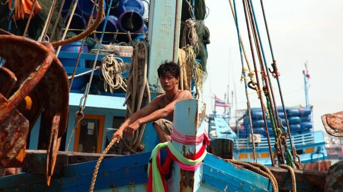 A fisher at the prow of a boat, mooring rope in hand, as the vessel arrives in port in Pattani, August 12, 2016.