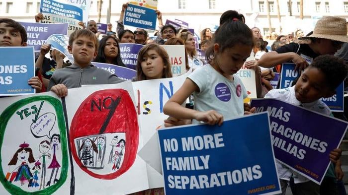 People hold signs to protest against U.S. President Donald Trump's executive order to detain children crossing the southern U.S. border and separating families outside of City Hall in Los Angeles, California, U.S. June 7, 2018.