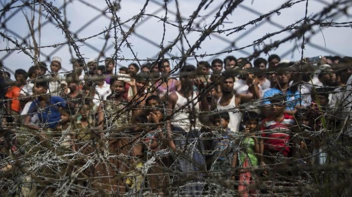 Rohingya refugees gather behind a barbed-wire fence in the “no-man’s land” border zone between Myanmar and Bangladesh, April 25, 2018.
