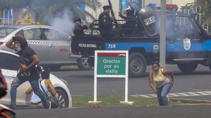 An officer of the National Police shoots at a group of people outside the shopping mall Metrocentro in Managua, Nicaragua, May 28, 2018. 