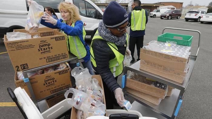 School workers load food packs as they distribute meals to students at Fairfield Middle School in Richmond, Virginia, March 18, 2020.