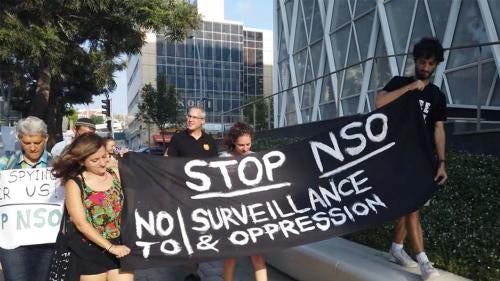 People holding sign to stop NSO