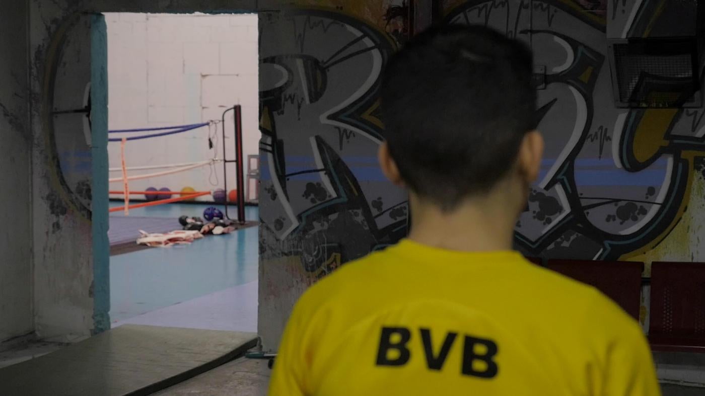 Boy in boxing gym with back towards camera