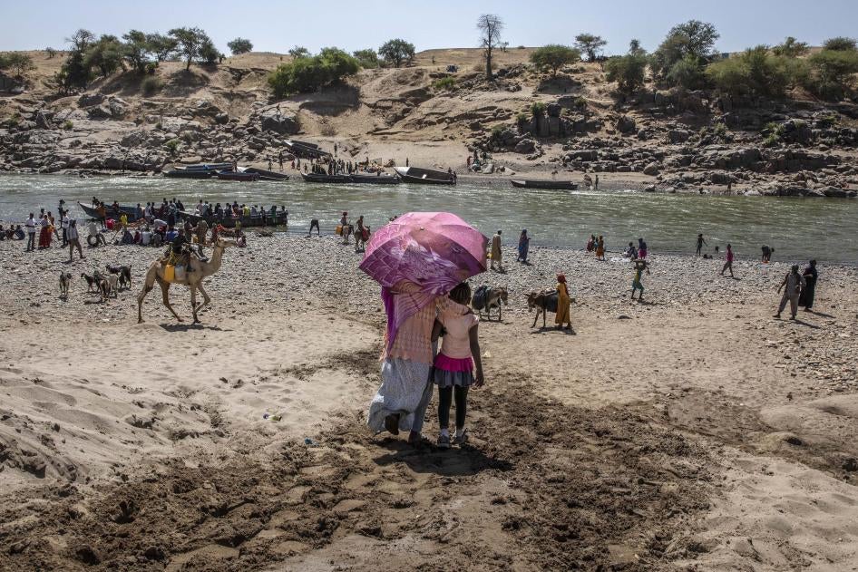 Des réfugiés ayant fui le conflit dans la région du Tigré en Éthiopie, en traversant la rivière Tekeze marquant la frontière entre l'Éthiopie et le Soudan, photographiés peu après leur arrivée sur le territoire soudanais, près de Hamdayet (est du Soudan), le 21 novembre 2020. 