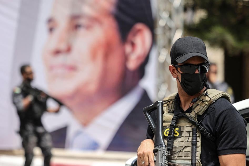 An Egyptian intelligence security detail member stands guard near a banner showing President Abdel Fattah al-Sisi.