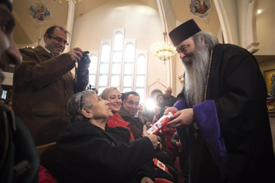 Lors d'un office religieux à l'Église apostolique arménienne St. Mary à Toronto, le 11 décembre 2015, le prêtre orthodoxe arménien Meghrig Parikian, à droite, remettait un Père Noël en chocolat à Gerget Prtoyan. Plus tôt dans la journée, cette église avait accueilli plusieurs réfugiés syriens.
