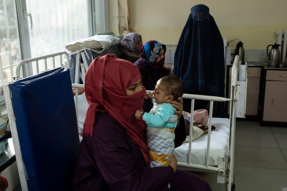 زنی نوزاد تحت درمان خود در بخش سوء تغذیه‌ی شفاخانه اطفال آتاتورک را در آغوش گرفته است.  کابل، افغانستان، ۲ دسامبر 2021. © 2021 AP Photo/Petros Giannakouris