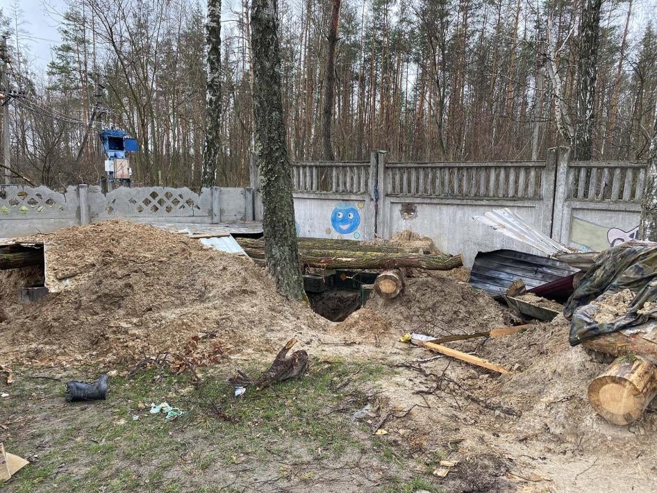 Российские военные вырыли окопы и укрытия в школьном дворе и позади школы, в подвале которой они удерживали свыше 350 местных жителей. Ягодное, 17 апреля 2022 г. 