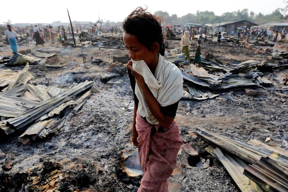 A Rohingya woman walks among debris