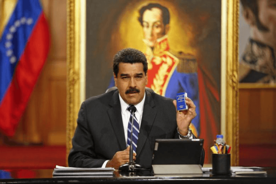 Venezuela's President Nicolas Maduro holds a copy of the country's constitution as he speaks during a news conference at Miraflores Palace in Caracas December 30, 2014.