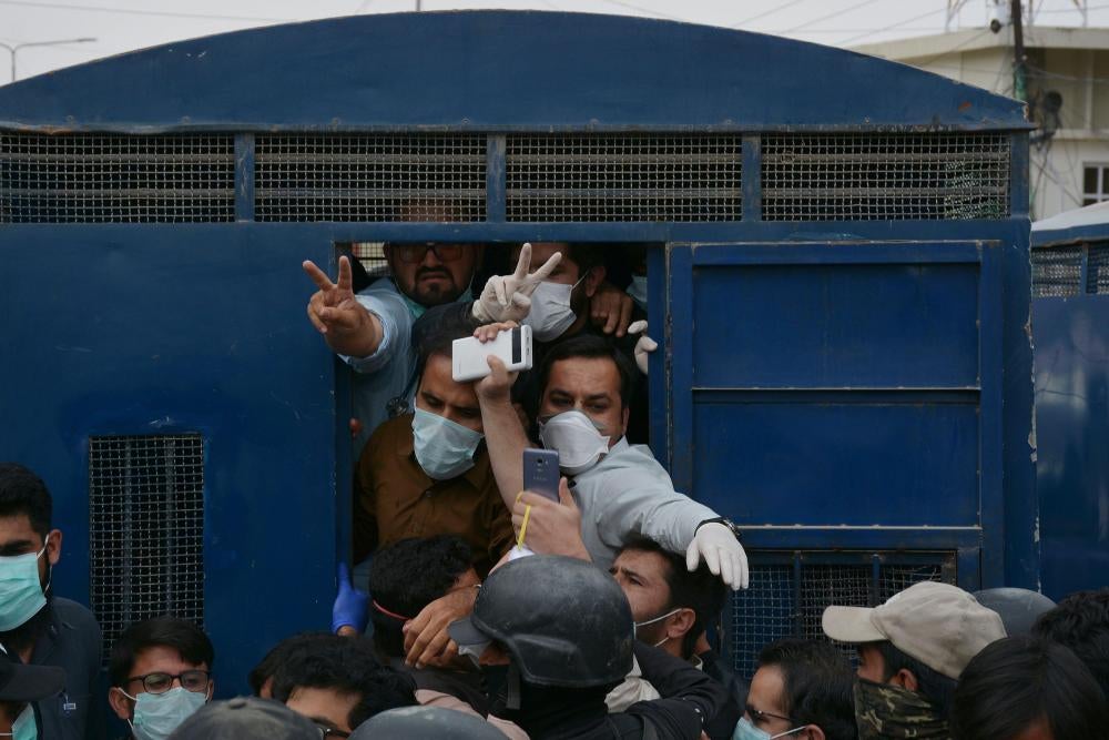 Men in masks being forced into a police van