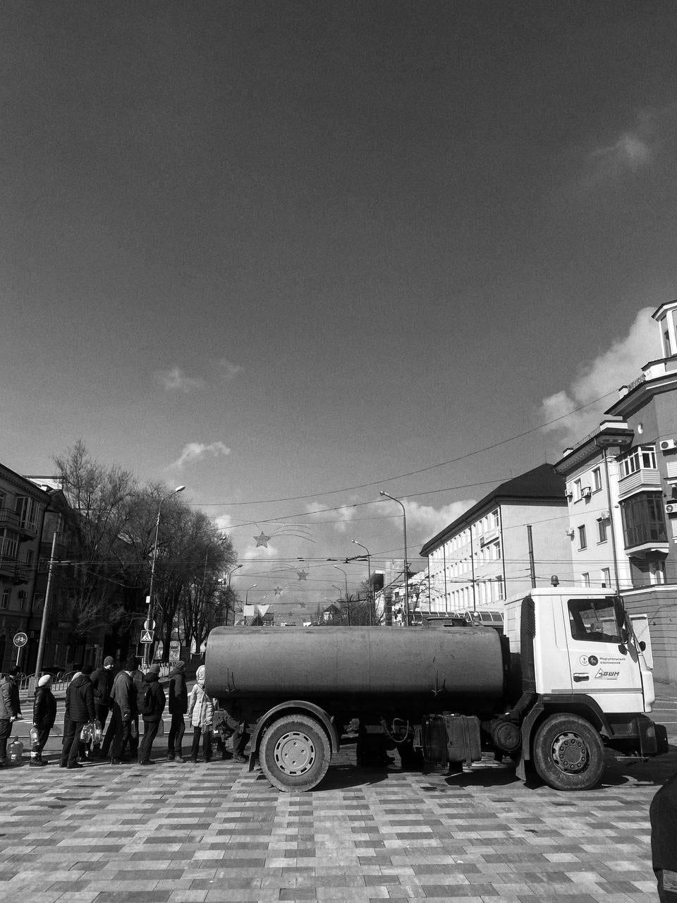 People without access to running water in Mariupol wait on line for water from a water truck
