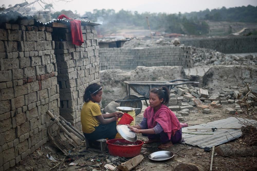 Nine-year-old Selina T. helps her friend Bipana L., 11, wash dishes and utensils in Lalitpur, Nepal where both girls live and work. Both girls work in a brick kiln to help their parents. Bipana attended school for only one day; Selina is still in school, 