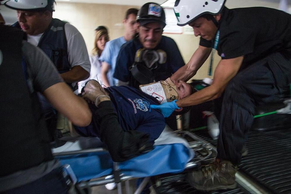 Voluntarios de primeros auxilios de la Universidad Central de Venezuela, que forman parte de una organización conocida como Cruz Verde, trasladan a una persona gravemente herida durante enfrentamientos con policías hasta un centro de salud cercano en Alta