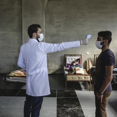 A medic checks the temperature of a man inside a health isolation centre which has been established on the Syrian-Turkish borders in order to place people coming from Turkey to Idlib as a preventive measure against the spread of COVID-19. 