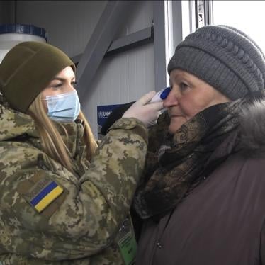 A soldier in a face mask checks the temperature of an older woman at a checkpoint in Mayorsk, Donetsk region, Ukraine, Monday, March 16, 2020.