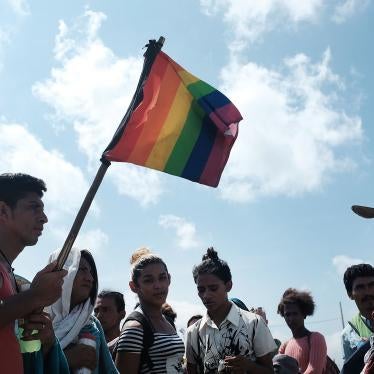 A group of men and women march walk while holding rainbow pride flags