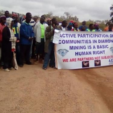 A group of protesters holds a sign that reads "Active Participation of Communities in Diamond Mining is a Basic Human Right."