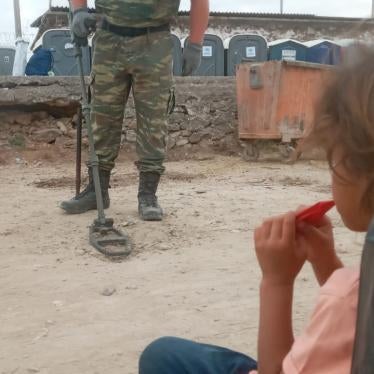 A girl from Syria living in Mavrovouni camp watches the Greek military search for unexploded munitions