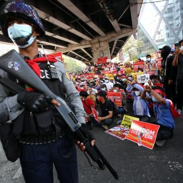 A police officer stands in front of anti-coup protesters in Yangon, Myanmar, February 19, 2021.