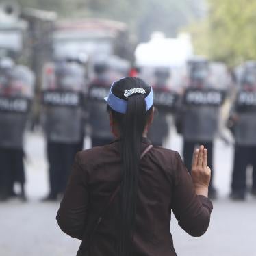 A protester flashes the three-fingered salute in front of police in Mandalay, Myanmar, February 20, 2021.