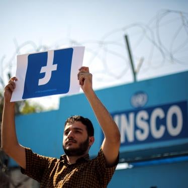 A Palestinian demonstrator holds a banner of the Facebook logo.