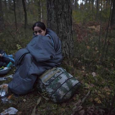 Two women and a child huddle in sleeping bags on the forest floor after crossing the Polish-Belarusian border near Michalowo on October 6, 2021.