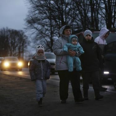 A family walks alongside a road at night with their belongings