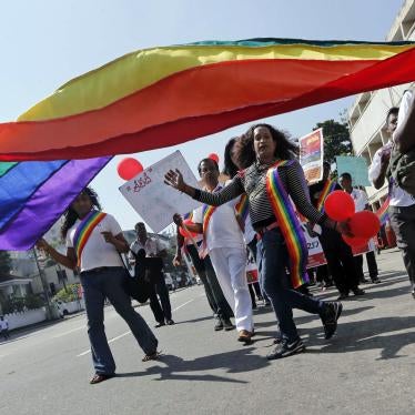 Activists march under a large rainbow flag