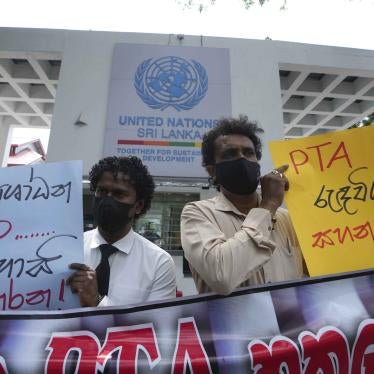 Two people hold protest signs written in Sinhalese 